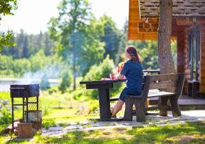 a woman sitting on a bench at a picnic table at Ezerkalni in Raiskums