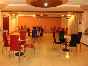 a dining room with tables and chairs and a clock at Hotel Mayfair in Lahore