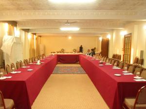 a long table with red tables and chairs in a room at Hotel Mayfair in Lahore