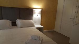 ein Schlafzimmer mit einem weißen Bett und einem Licht an der Wand in der Unterkunft Maison d'Elite Guest House in Venedig