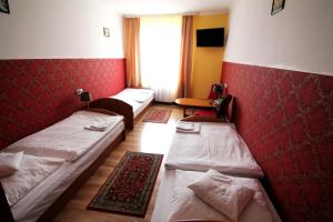 three beds in a room with red walls at FusGym Resort in Ożarów Mazowiecki