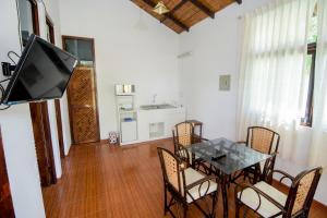 a dining room with a table and chairs and a television at La Choza Bungalows in Tambo Grande