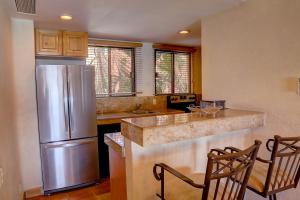 a kitchen with a stainless steel refrigerator and two chairs at Condominios La Luna - Ocean Front in Cabo San Lucas