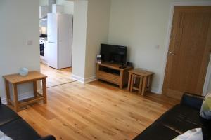 a living room with a couch and a flat screen tv at Highlands Apartment 2 in Shanklin