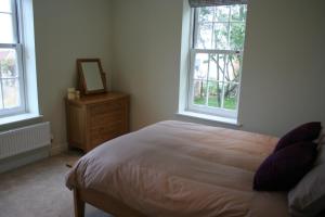 a bedroom with a bed and a dresser and two windows at Highlands Apartment 2 in Shanklin