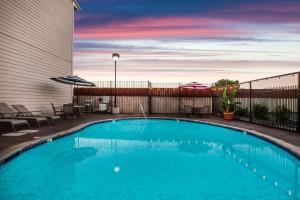 a pool with chairs and umbrellas next to a building at Days Inn & Suites by Wyndham Antioch in Antioch