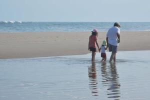 un hombre y dos niños parados en la playa en Mill House Inn, en East Hampton