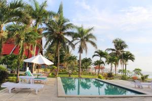 a pool with palm trees and a table and chairs at Aman Gati Hotel Lakey in Huu