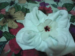 a white towel with white flowers on a bed at Hotel California in San Jorge