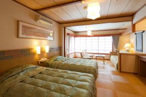 a bedroom with two beds and a table and a desk at Kasuien Minami in Matsue