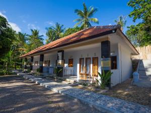 a small white house with a palm tree at Bintang Hostel and Homestay in Nusa Penida