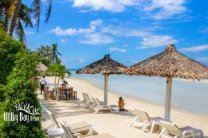 una playa con sillas y sombrillas y el océano en Milky Bay Resort, en Baan Tai