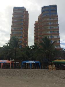 two tall buildings on a beach with palm trees at Apartamento en Atacames con vista al mar in Atacames