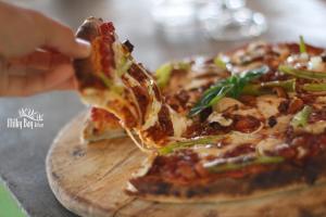 a person eating a slice of pizza on a cutting board at Milky Bay Resort in Baan Tai