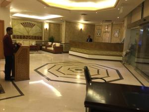 a man standing in a lobby with a geometric floor at Continental Residence in Kuwait