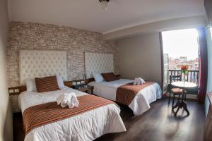 Habitación de hotel con 2 camas y ventana en Ureta Hotel en Cusco