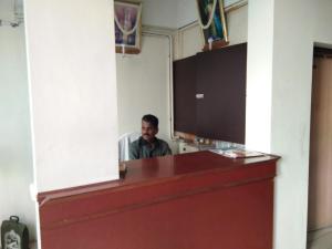 a man sitting at a desk in a room at Hotel John in Kanyakumari
