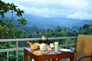 a table with books and drinks on a balcony with a view at Mistletoe Homestay & Cafe in Munnar