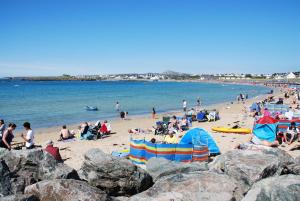 a group of people on a beach near the water at The Beach Motel in Trearddur