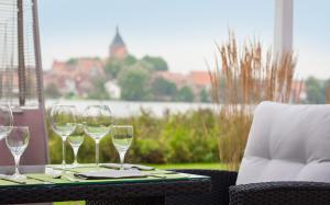 a table with wine glasses on a table with a chair at Seehotel Schwanenhof in Mölln