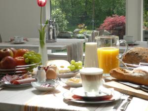 una mesa de desayuno con productos de desayuno y zumo de naranja en Gästehaus Wahnenmühle, en Erkrath