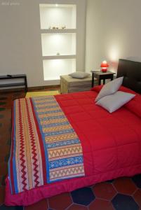 ローマにあるAppartamento a uso turisticoの赤いベッド(カラフルな毛布付)