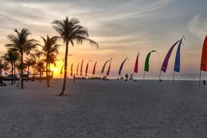 un groupe de pavillons sur une plage bordée de palmiers dans l'établissement Villa Agung, à Nusa Lembongan