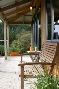 un banc en bois assis sur une terrasse couverte avec une table dans l'établissement Abseil Inn, à Grottes de Waitomo