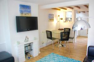 uma sala de estar com uma mesa e cadeiras e uma televisão em Seaside Fisherman Cottage Southwold em Southwold