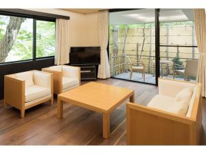 a living room with a table and chairs and a television at Auberge Suzukane in Koriyama