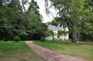 a white house with a tree and a dirt road at Château de La Villette in Ardentes