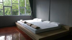 a bed sitting in a room with two windows at Inn Stations Hostel in Bangkok