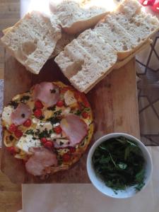 a wooden cutting board with a pizza and some bread at Eszter Guesthouse in Sîncrăieni