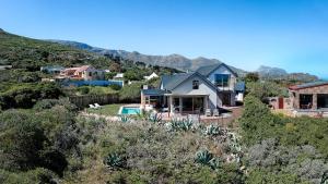 a house on top of a hill with mountains in the background at Willow Beach House - with backup power in Noordhoek