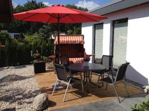 a table and chairs under a red umbrella on a patio at Moderne-Ferienwohnung-in-ruhiger-Lage in Quickborn