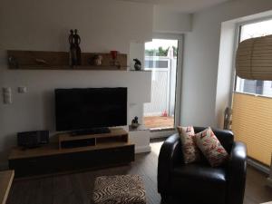 a living room with a flat screen tv and two chairs at Moderne-Ferienwohnung-in-ruhiger-Lage in Quickborn