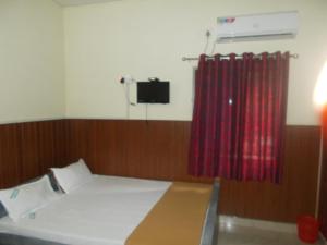 a bedroom with a bed and a red curtain at Avanti Inn in Guruvāyūr