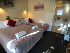 a bedroom with two beds with red and white pillows at Tui Lodge Motel in Christchurch