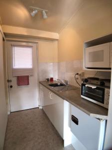 a small kitchen with a sink and a microwave at Tui Lodge Motel in Christchurch