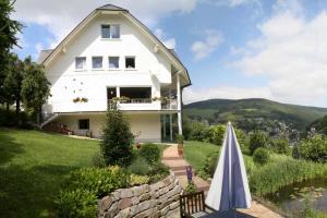 a white house with an umbrella in front of it at Landhaus Mühlenberg in Willingen