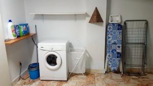 a laundry room with a washing machine and a snowboard at Magoito Beach Apartment in Sintra