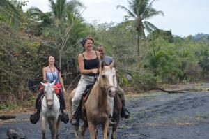 a group of people riding horses down a dirt road at Finca Valeria Treehouses Glamping in Cocles