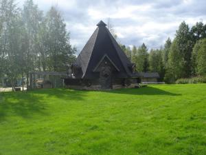 a small building with a pointed roof in a field at Toola-Lodge in Syöte