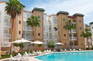 a hotel with a swimming pool with chairs and umbrellas at Al Kawtar in Mohammedia