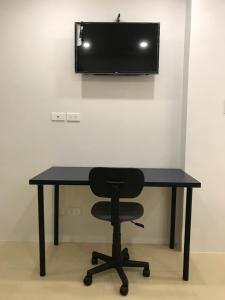 a black desk with a chair and a television on a wall at Umali Kayo at Megatower Residences II in Baguio