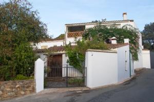 una casa blanca con una puerta y una valla en La Rana Verde Casa Rural, en Los Romeros