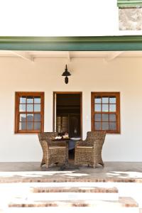 un patio con 2 sillas de mimbre y una mesa en d'Olyfboom Guest House B & B, en Paarl