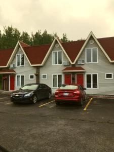two cars parked in a parking lot in front of a building at Restland Motel in Clarenville