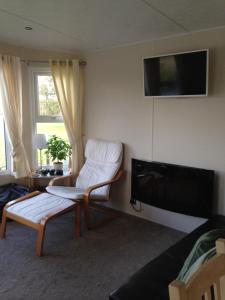 sala de estar con silla y TV de pantalla plana en Marshlands Lakeside Nature Retreat, en Barton-upon-Humber