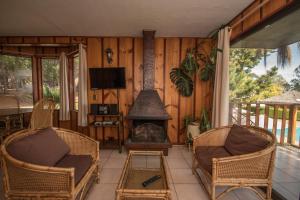 sala de estar con chimenea, sillas y TV en Pao Pao Lodge Algarrobo, en Algarrobo
